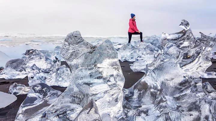 Un touriste marchant sur les blocs de glace de la plage de diamants