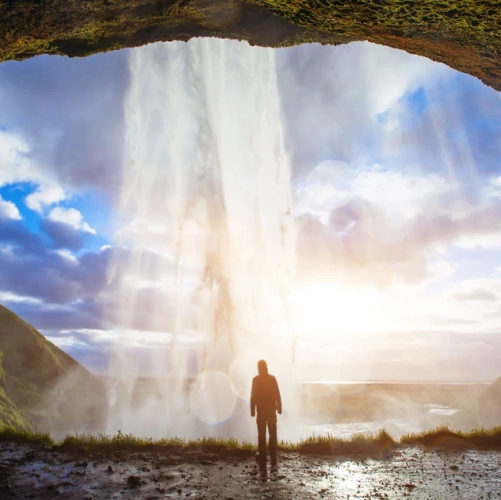 Un touriste derrière les eaux de la chute de Seljalandsfoss