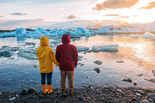 Un couple de touriste admirant les icebergs flottants du Jokulsarlon